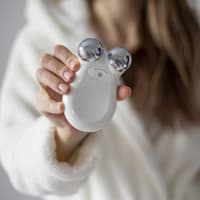 Frau hält ein Mikrostromgerät zur Massage des Gesichts in ihren Händen