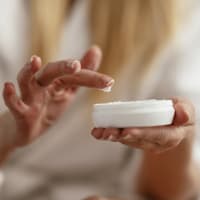 Frau cremt ihre Hände ein.