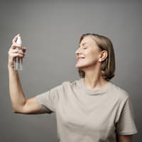 Frau sprüht Gesichtsspray in ihr Gesicht.