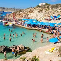 Viele Touristen am Strand im Wasser und unter Sonnenschirmen.