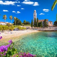 Strand mit ein paar Handtüchern, Palmen und einer Kirche im Hintergrund