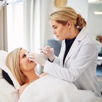 Was du über eine Hyaluronsäure Unterspritzung wissen solltest, erfährst du hier von einer Fachärztin. Frau bei einem kosmetischen Eingriff.