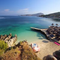 Ein Blick auf den Strand und das Meer von Ksamil mit Sonnenschirmen und Liegen.