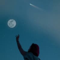 Frau streckt Arm zum Mond