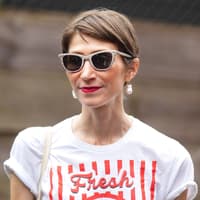 Lip Stain zaubert den ganzen Tag frische Lippenfarbe. Frau mit braunhaarigem Kurzhaarschnitt, einer beigen Sonnenbrille und roten Lippen.