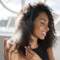 Frau sprüht Spray in die Haare