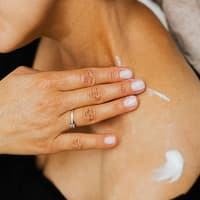 Frau cremt Schulter ein