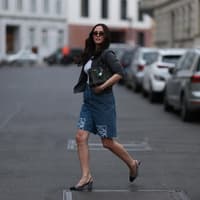 Frau mit dunklen Haaren und Sonnenbrille trägt Jeans-Shorts mit Slingback-Pumps.