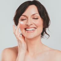 Frau trägt Gesichtscreme auf.