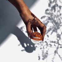 Frau hält eine kleine Dose mit Vaseline in der Hand.