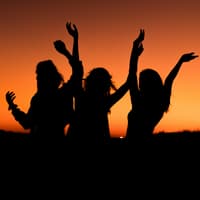 Drei Sternzeichen lassen sich nicht unterkriegen, sondern blühen nach einer Trennung erst richtig auf. Drei Frauen tanzen ausgelassen vor dem Sonnenuntergang.