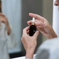 Frau hält Hautpflegeserum in der Hand.