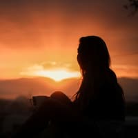 Frau schaut in den Sonnenaufgang