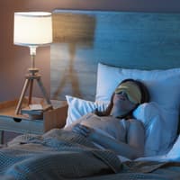 Frau schläft im Bett mit Schlafmaske