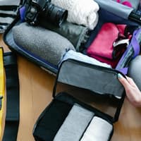 Ordnung im Koffer ist das A und O, um Platz zu sparen. Voller Koffer mit Kleidung, Kamera und Sortierfächern.