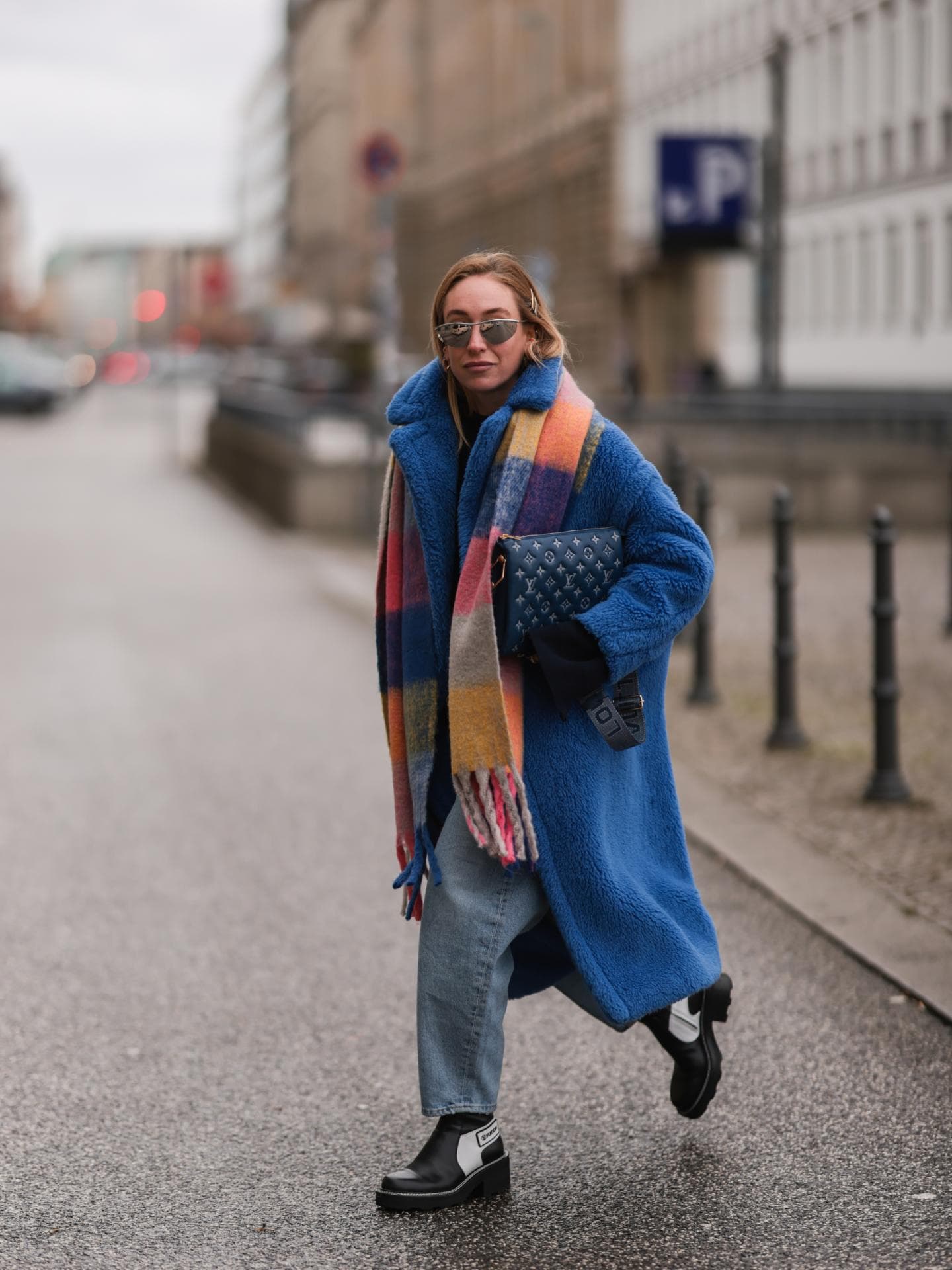 Streetstyle Frau trägt Jeans, blauen Mantel und bunt karierten Schal