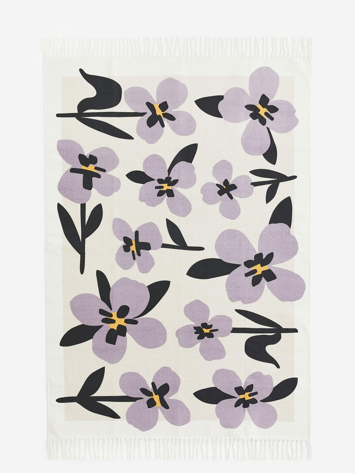 Gemusterter Flachgewebeteppich von H&M Home Home mit großflächigen Blumen. 