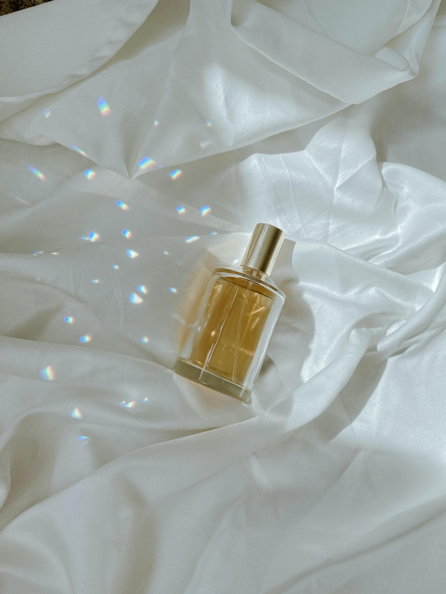 Parfum Flakon liegt auf einem Bettlaken mit Licht und Schatten
