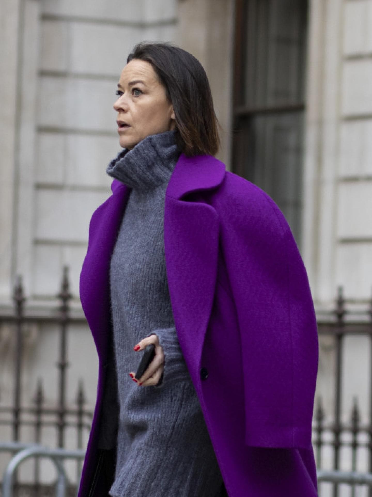 Frau mit grauem Pullover und lila Mantel