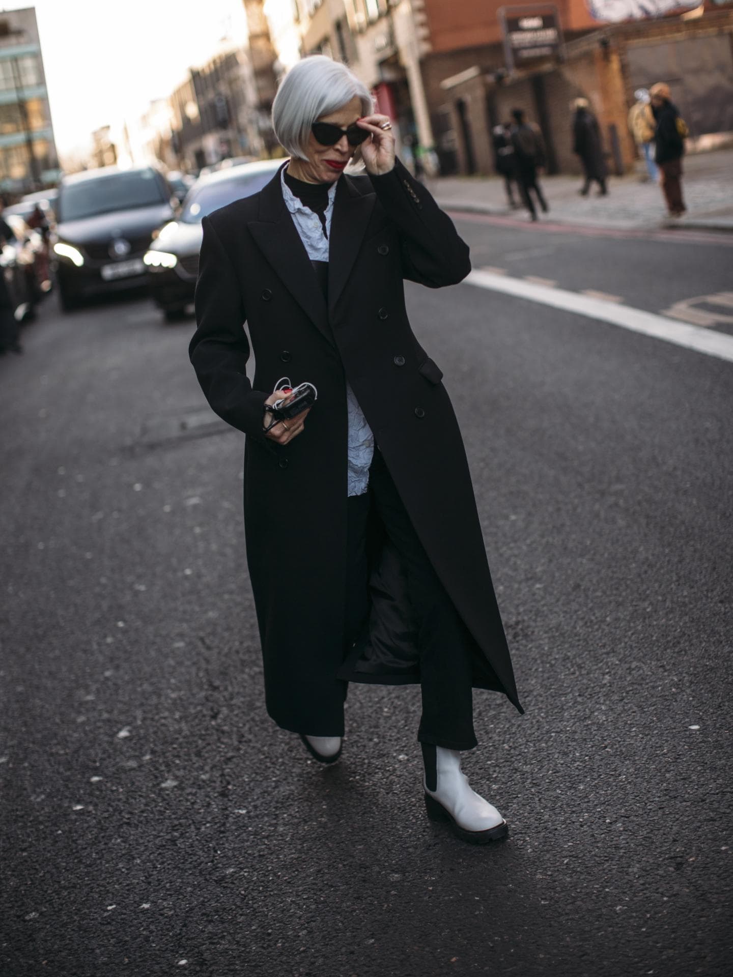 Frau trägt auf Fashion Week in London Stiefeletten mit Hose und Mantel Ankle Boots kombinieren