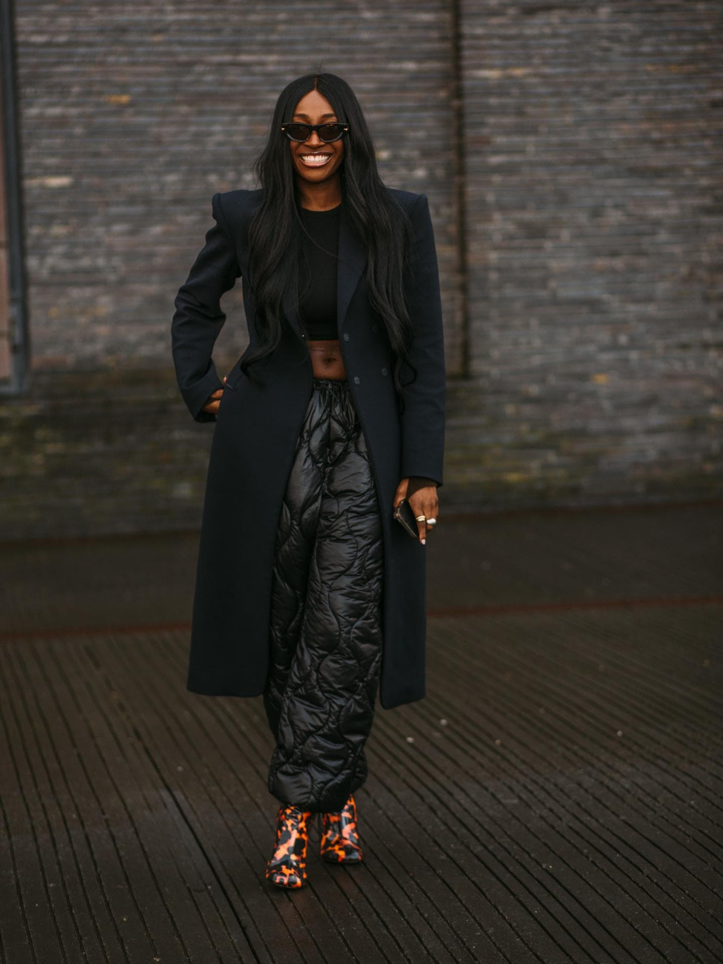 Frau trägt auf Kopenhagen Fashion Week Ankle Boots gesteppte Hose und schwarzen Mantel Ankle Boots kombinieren