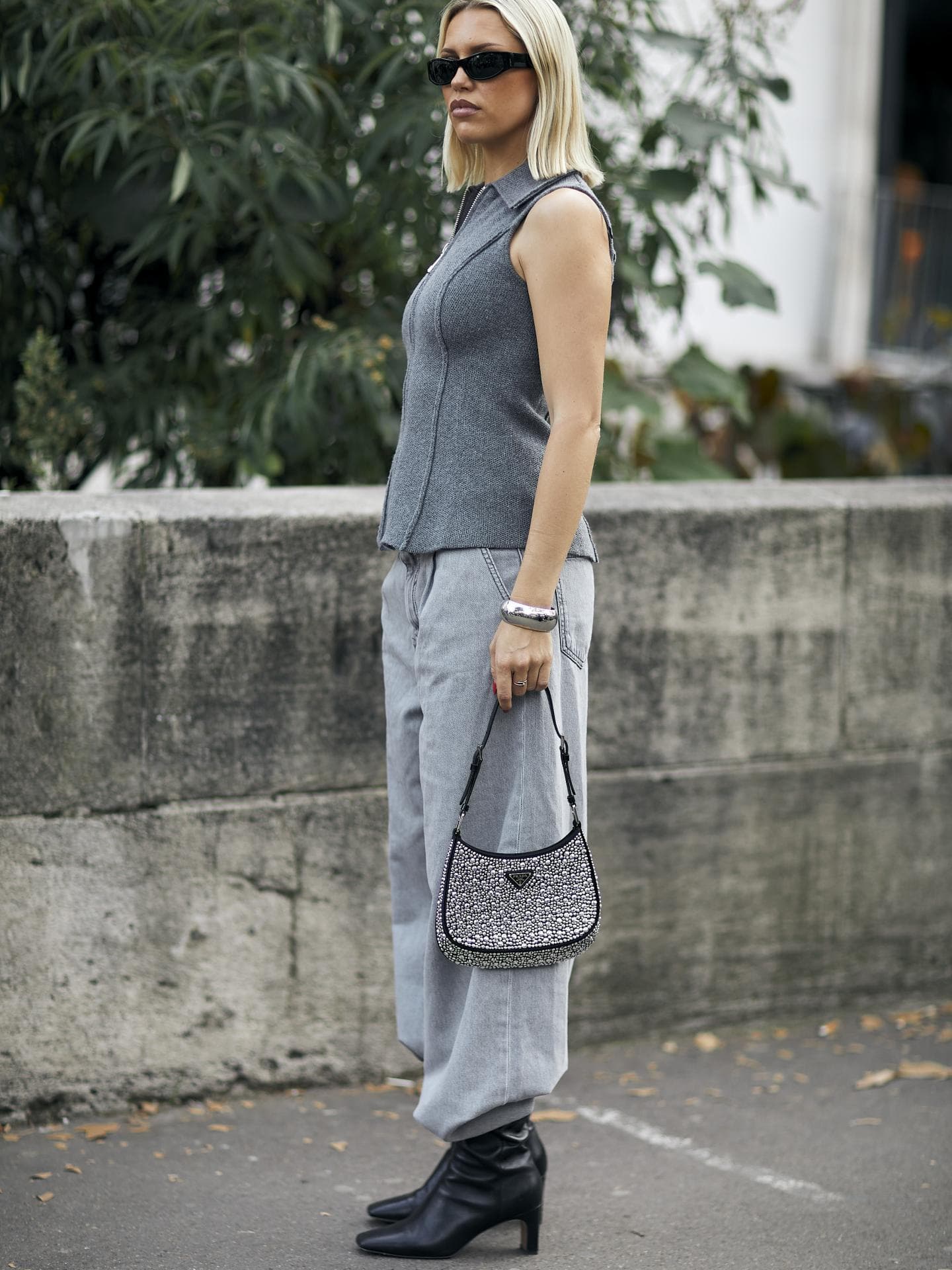 Frau trägt auf Paris Fashion Week Ankle Boots mit grauer Jeans, grauem Top und Sonnenbrille