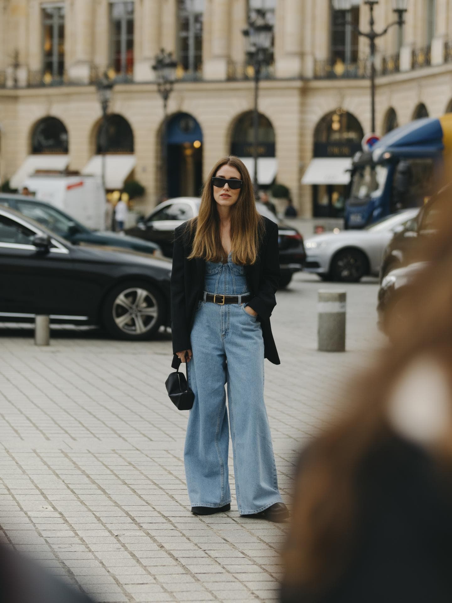 Frau trägt weite blaue Jeans mit schwarzem Blazer und Sonnenbrille sowie Jeans Top