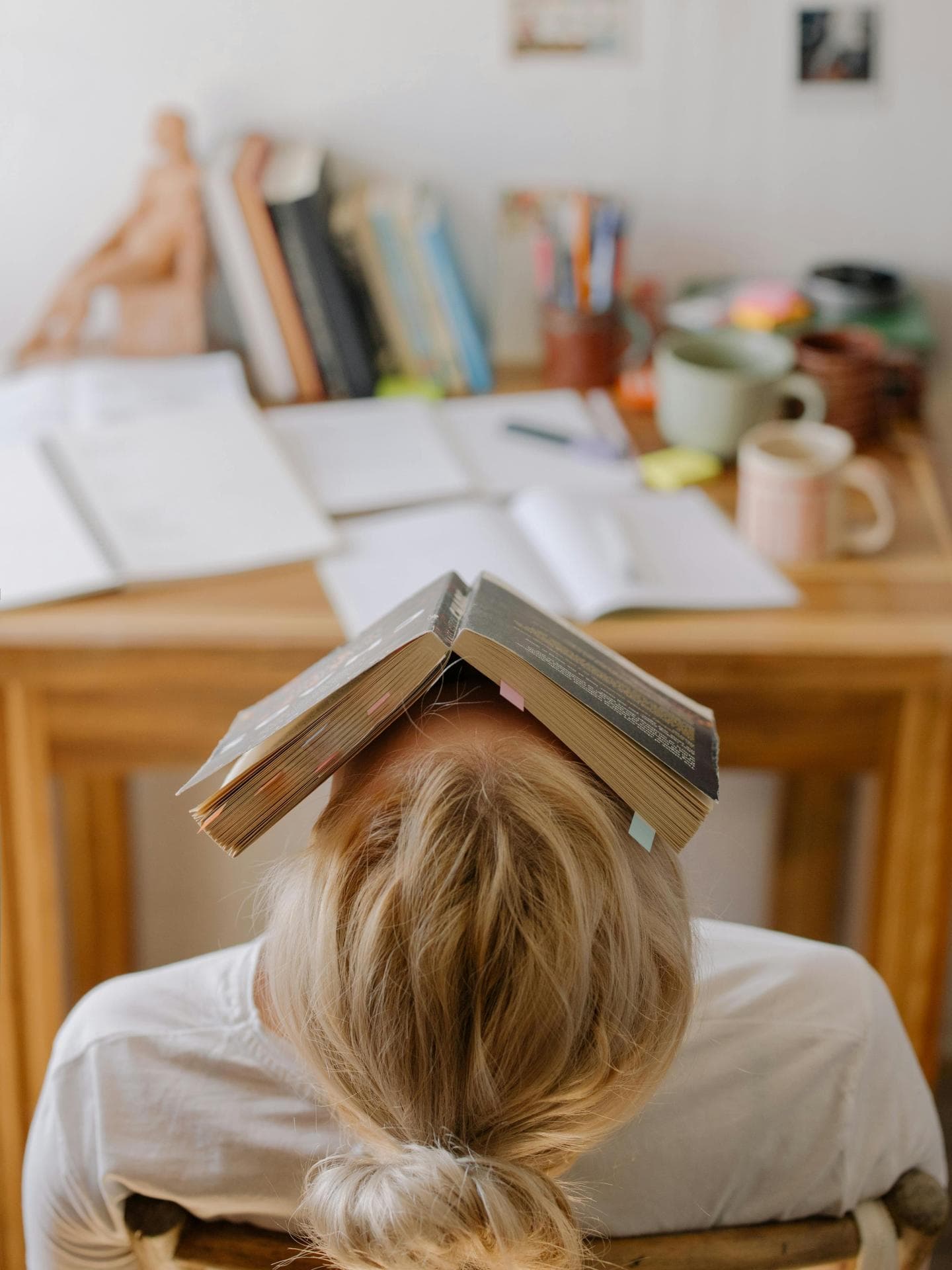 Toxische Produktivität Gestresste Frau mit Buch auf dem Kopf
