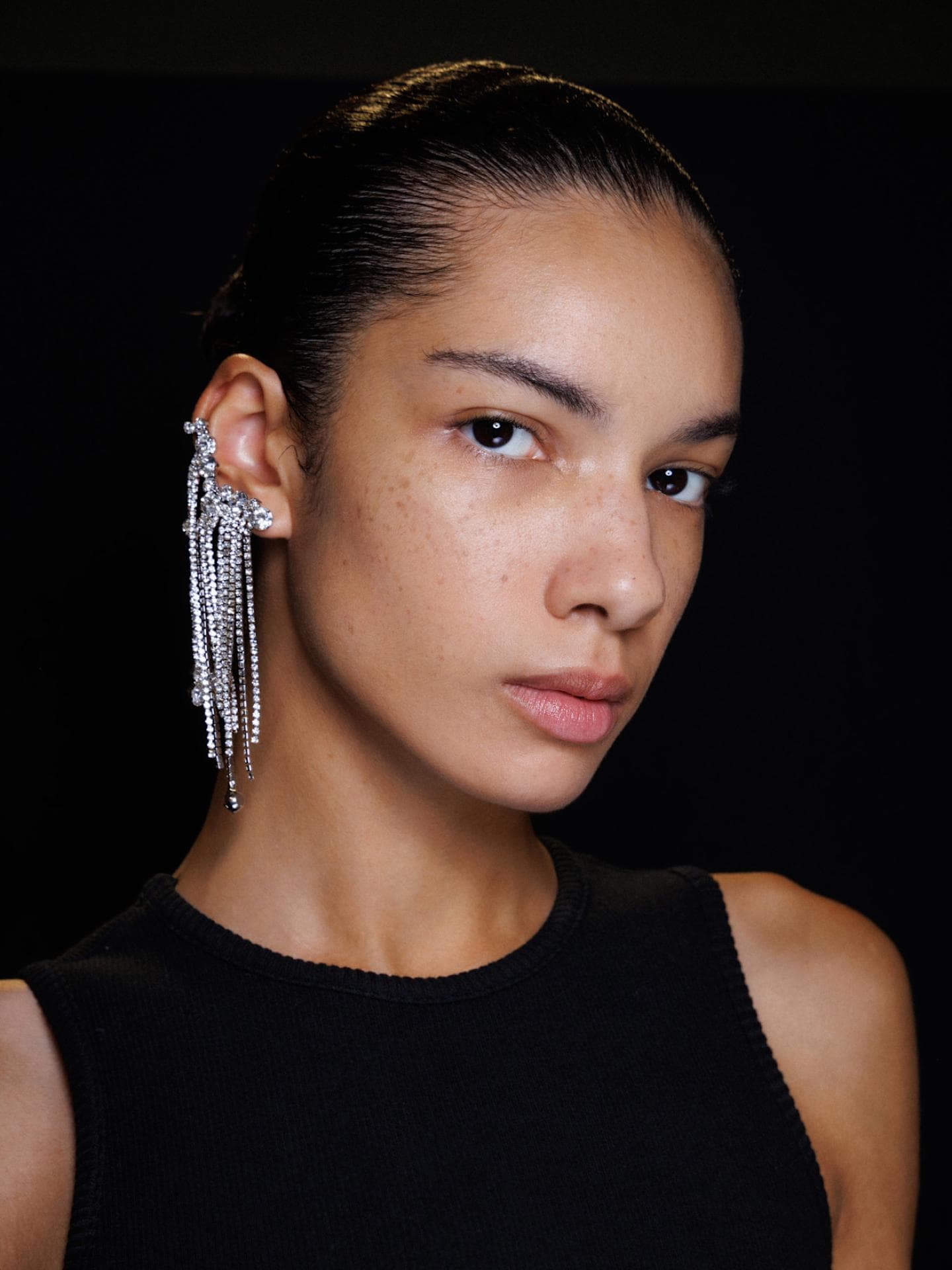 Straight Brows sehen natürlich und elegant aus. Portrait einer Frau mit glitzernden, langen Ohrringen.