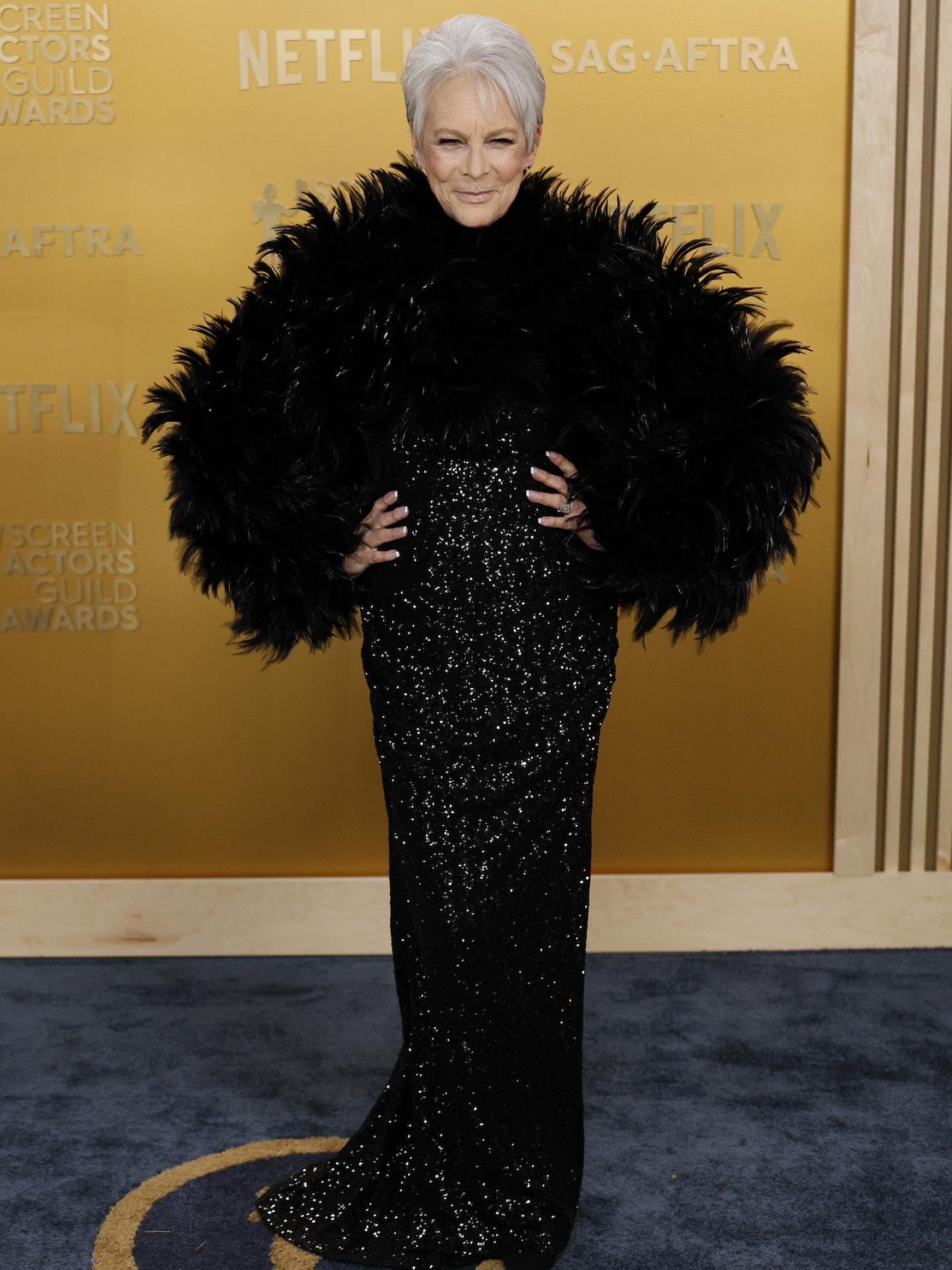 Jamie Lee Curtis mit einem Paillettenkleid und Feder-Bolero.