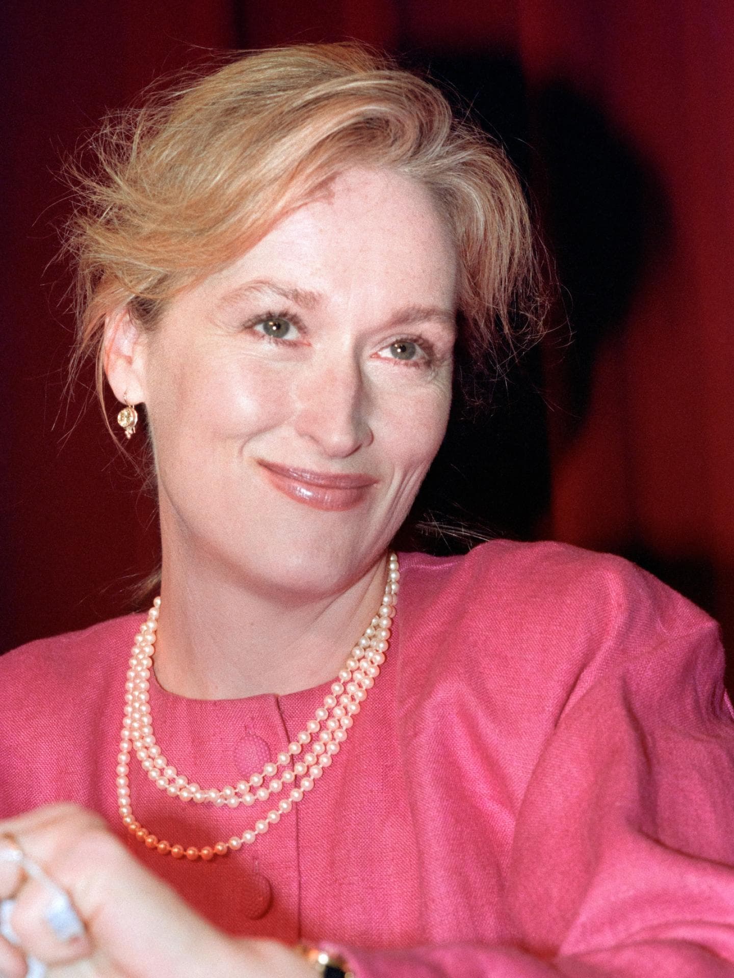 Meryl Streep mit drei Perlenketten und einem pinken Oberteil.