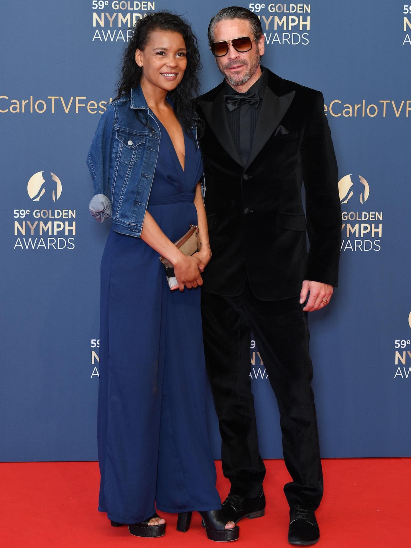 Ola Rapace in einem schwarzen Samt-Anzug mit Begleitung einer Frau in einem dunkelblauen Kleid.