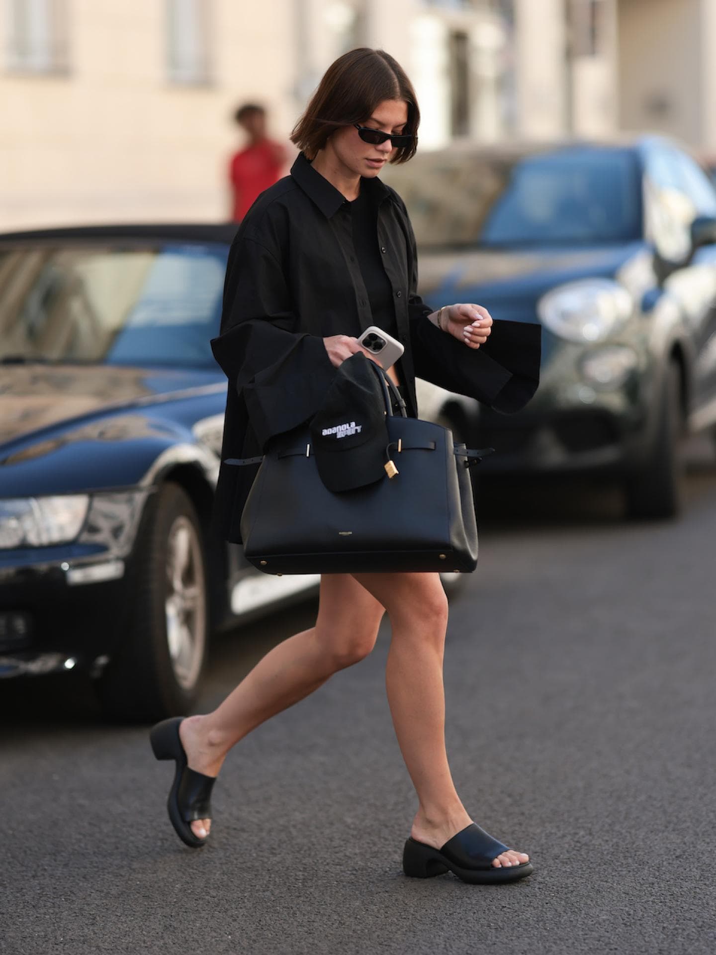 Junge Frau mit braunen Haaren, einer großen Tasche und schwarzen Leder-Sandalen.