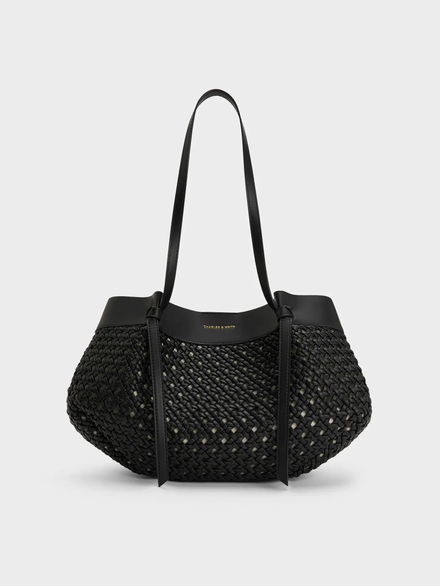 Gewebte Tote Bag in Schwarz mit langen Henkeln vor einem hellen Hintergrund.