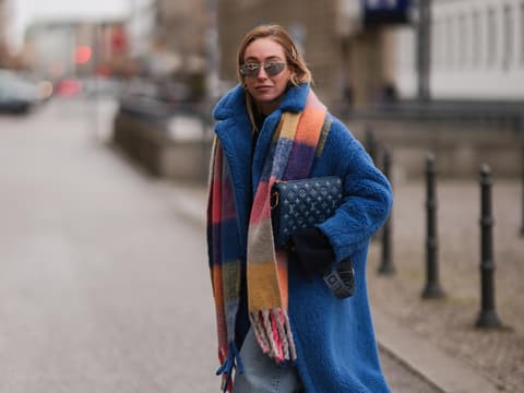 Streetstyle Frau trägt Jeans, blauen Mantel und bunt karierten Schal