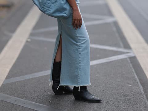 Eine Frau trägt einen Jeansrock und schwarze Stiefeletten