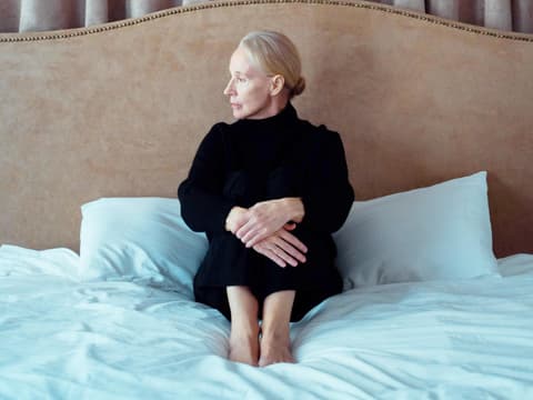 Frau sitzt traurig auf dem Bett