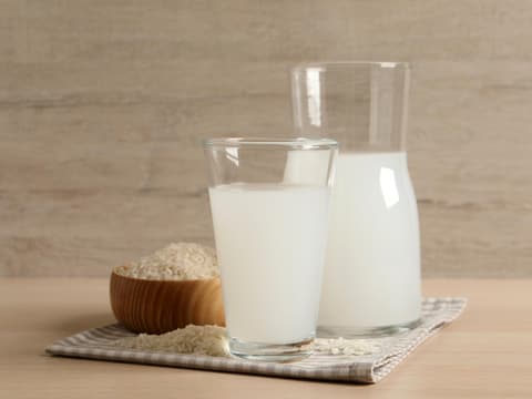 Reiswasser Ein Glas Reiswasser und eine Karaffe stehen auf einem Tisch