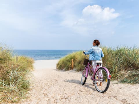 Reiseziele in Ostdeutschland Frau auf Fahhrad an einem Strand in Ostdeutschland