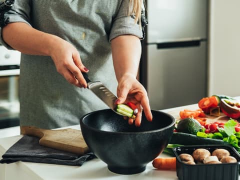 Zucchini-Paprika-Pfanne Frau bereitet Gemüse in der Küche zu