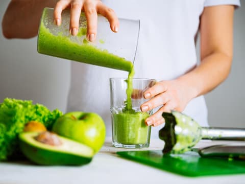 Grüner Smoothie Frau im weißen T-Shirt bereitet einen grünen Smoothie vor