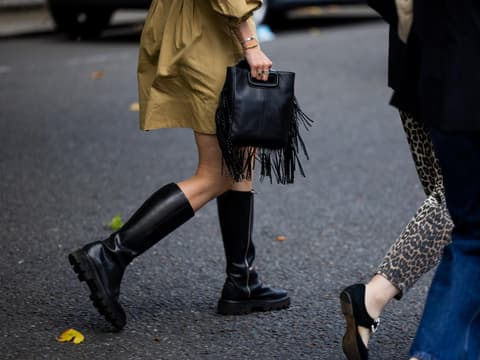 Stiefel in Wildlederoptik von Tamaris, die zum Kleid passen Frau mit schwarzem Stiefel und Fransen-Handtasche