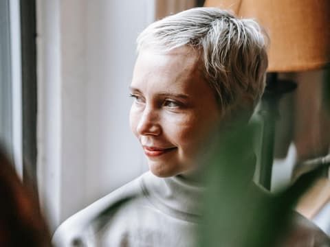 Frau schaut nachdenklich aus dem Fenster