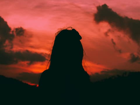 Silhouette einer Frau vor einem roten Himmel