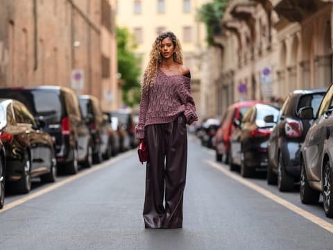 Eine Frau trägt einen dunkelroten Strickpullover mit einer Lederhose.