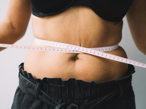 Maßband um den Bauch einer Frau
