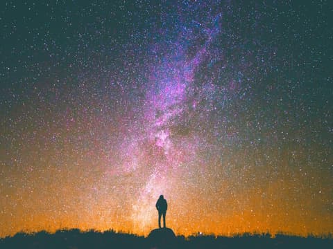 Welche 4 Sternzeichen im Oktober eine positive Wandlung erleben, erfährst du hier. Frau steht unter Sternenhimmel