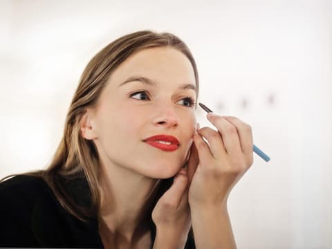 Frau trägt sich Kajal auf die Augen auf.