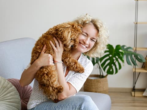 Manche Haustiere passen zu deinem Sternzeichen besser als andere. Frau kuschelt mit einem Hund.