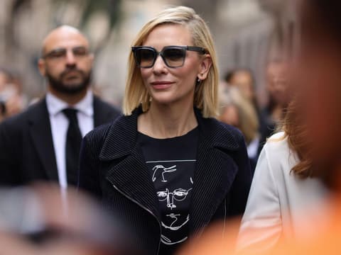 Frau mit blonden kurzen Haaren, seitlichem Scheitel und Sonnenbrille.